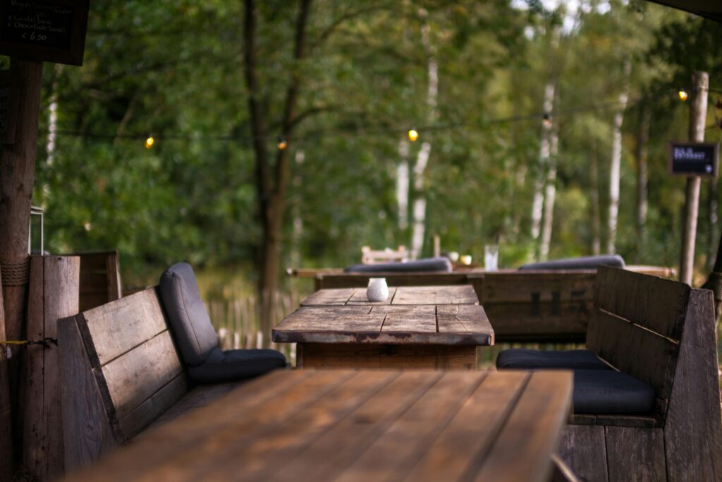 Rustic wooden cafe tables and benches in a serene forest setting in Lage Vuursche, Netherlands.